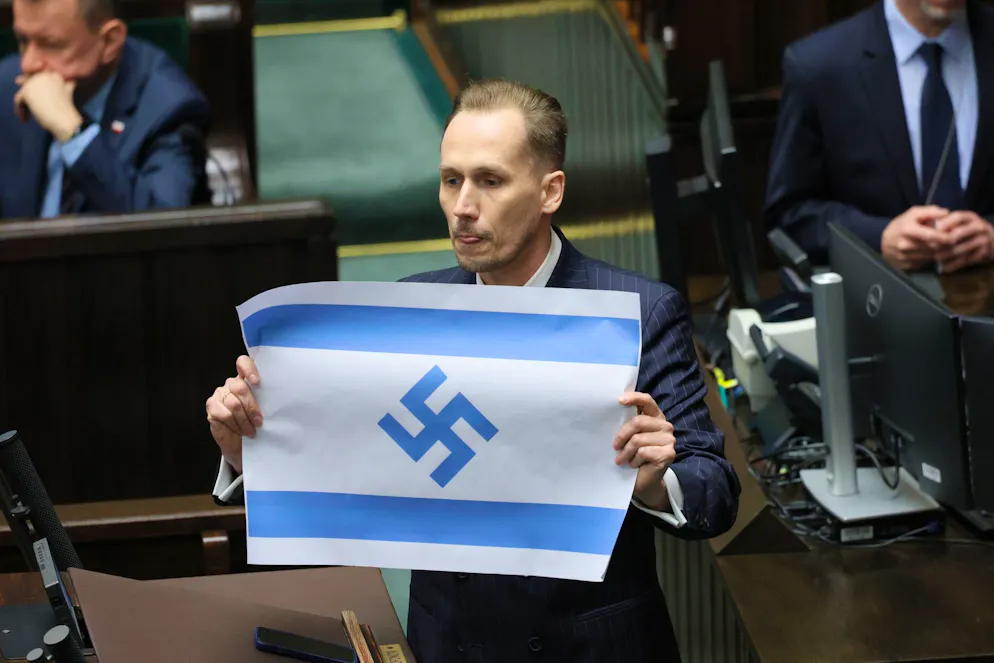 Konrad Berkowicz, député du parti d'extrême droite polonais Konfederacja, brandit un drapeau israélien orné d'une croix gammée au Sejm à Varsovie, en Pologne, le 14 avril 2026.