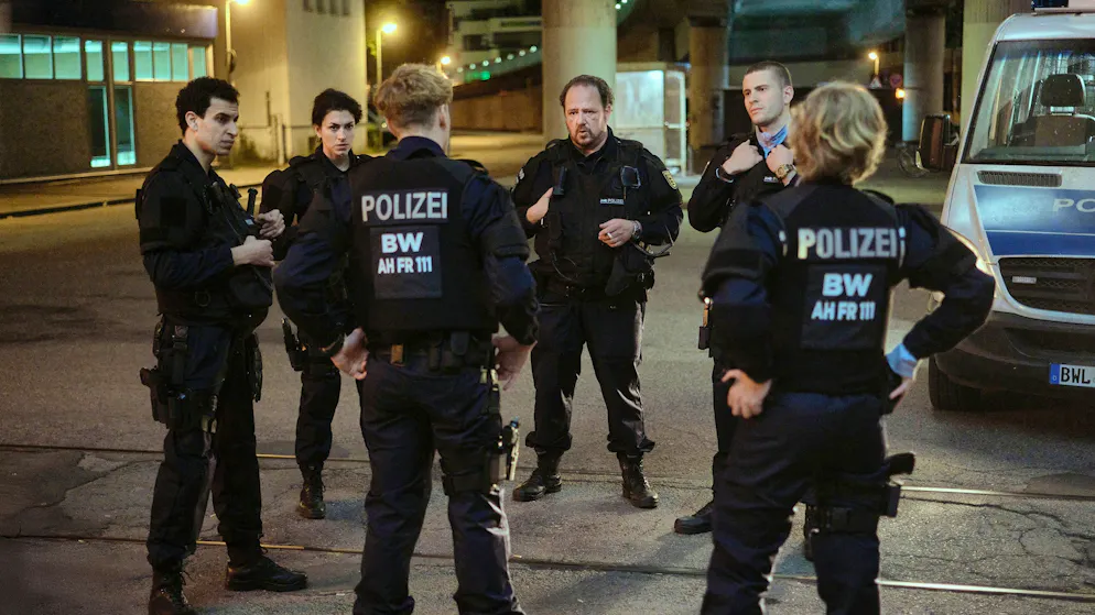 «Tatort» im Check – Eine Nacht, drei Schauplätze: Diese Filme kamen mit wenig Raum aus. Sechs Bereitschaftspolizist*innen diskutieren, was sie in der Diskothek erlebt haben. Einsatzleiter Wolle Heizmann (Andreas Anke, dritter von links) ist sich uneins mit Mahmoud (Mouataz Alshaltouh, links), Mariam (Anna Bardavelidze, zweite von links), Jakub (Lasse Lehmann, dritter von links), Timo (Ben Felipe) und Pia (Caroline Hellwig).