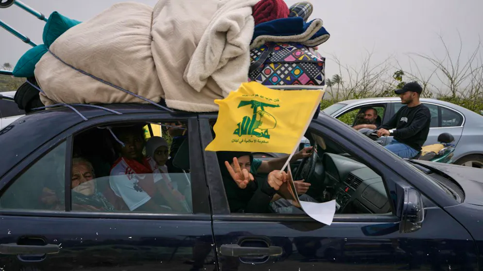 Une femme déplacée brandit un drapeau du Hezbollah en retournant dans son village.