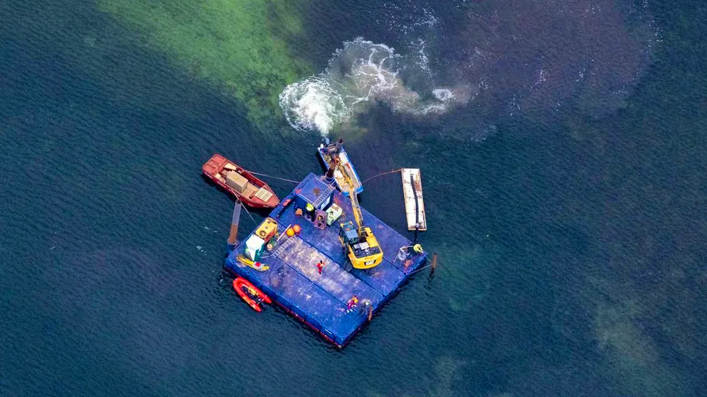 A work pontoon with an excavator and smaller escort boats approach the stranded humpback whale off the island of Poel yesterday, Saturday.
