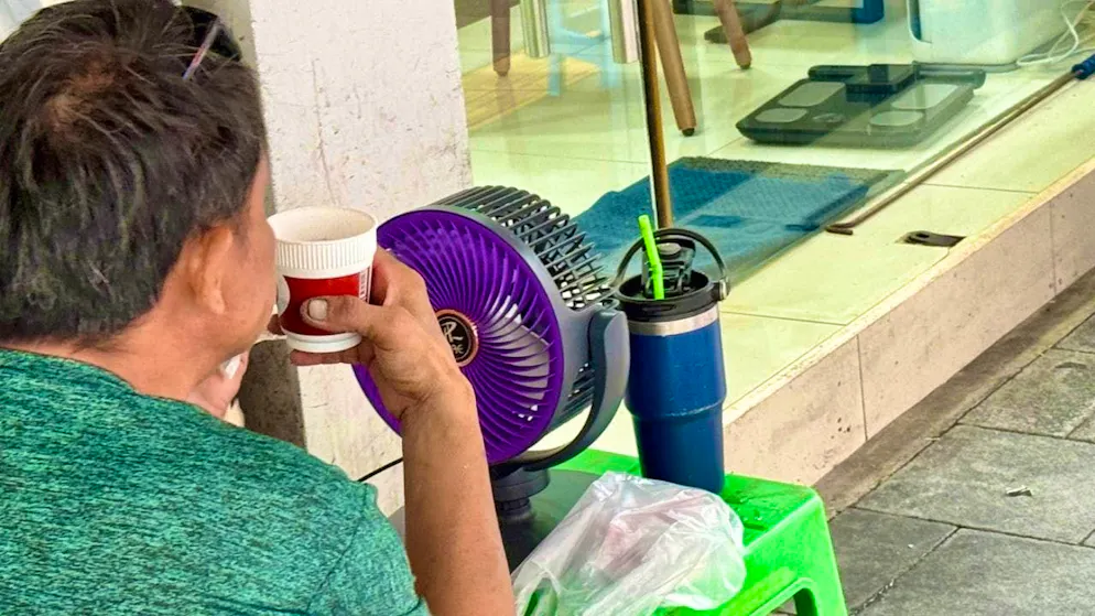 A man uses a fan to refresh himself in the heat. Photo: Carola Frentzen/dpa