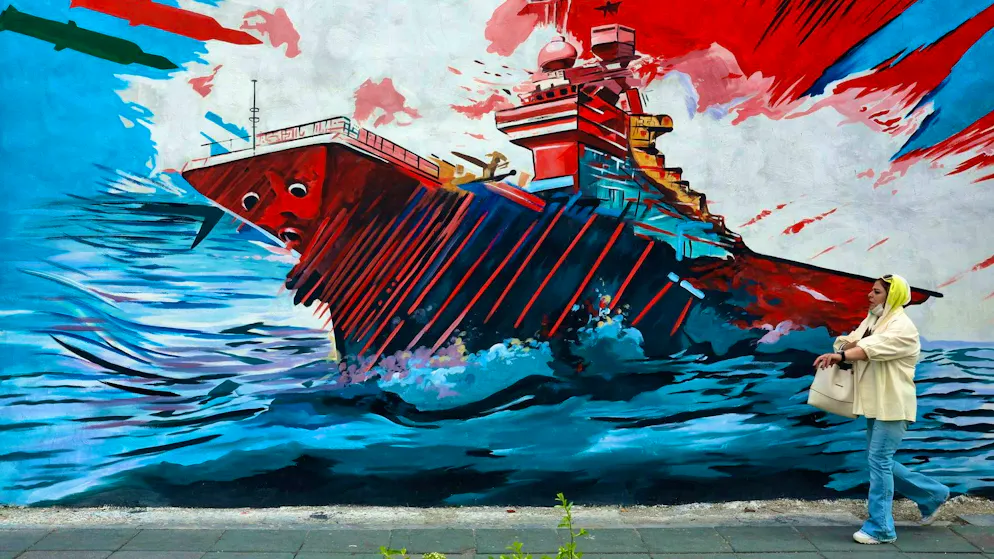 A woman walks past an anti-US and anti-Israel mural in Tehran. (Apr 20, 2026)
