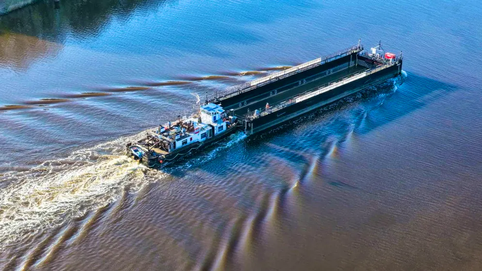 A barge, pushed by the push boat "Hans", is sailing on the Kiel Canal near Hohenhörn. The so-called barge, which is intended to transport the whale through the Baltic Sea to the North Sea, is due to arrive at the island of Poel next night or early Monday morning. (Photo taken with a drone) Photo: Bodo Marks/dpa