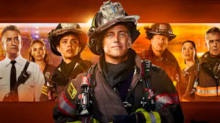 Cast von Chicago Fire Staffel 14 mit Taylor Kinney und Dermot Mulroney in Einsatzkleidung vor einem glühenden, orangefarbenen Hintergrund. 