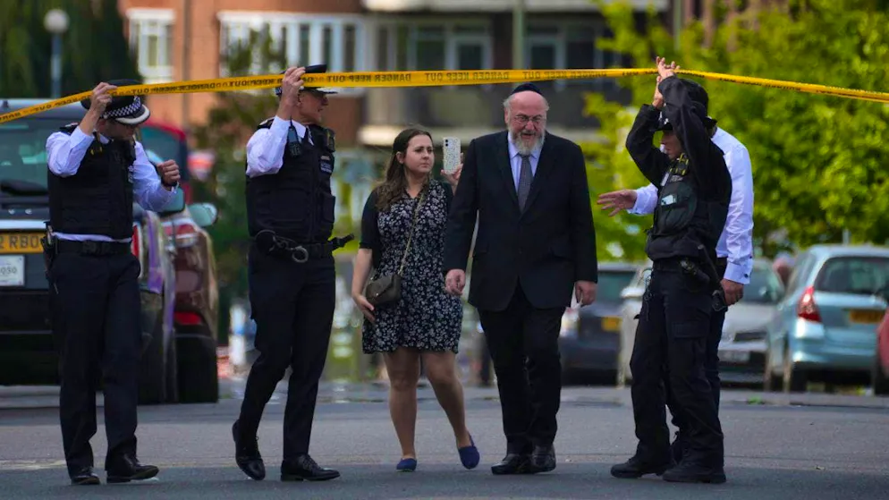 Police officers open the cordon for Chief Rabbi Ephraim Mirvis after two people were injured in a knife attack in the Golders Green area of London. Photo: Kin Cheung/AP/dpa