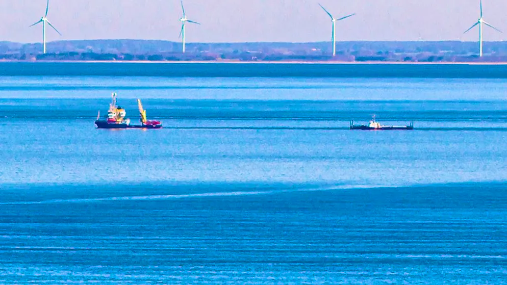 dpatopbilder - A ship pulls the barge with the beached whale off Fehmarn. The Danish coast can be seen in the background. Photo: Bodo Marks/dpa