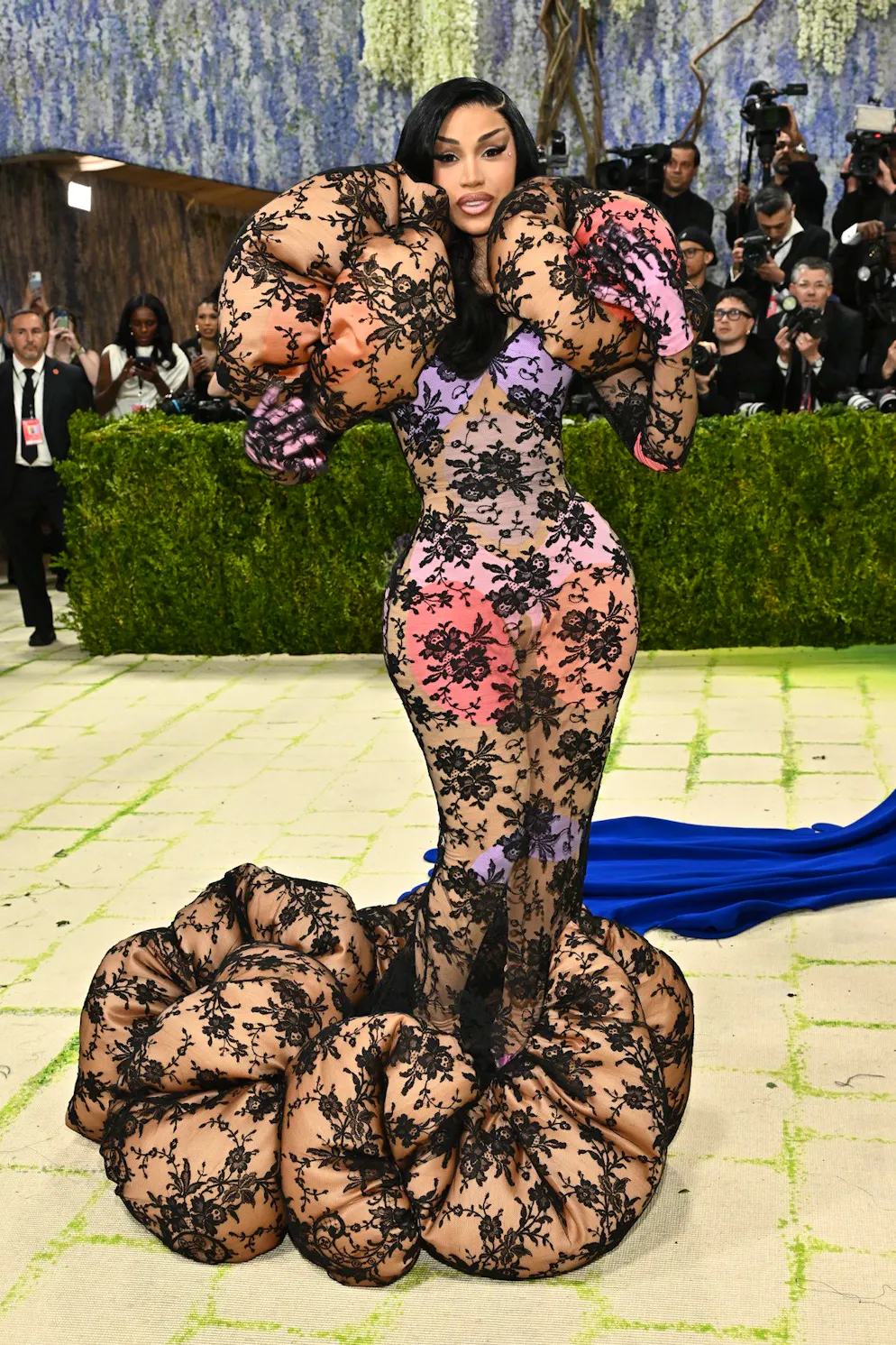 MET Gala – die Looks vom roten Teppich. Cardi B inszeniert ein Spiel der Proportionen: Ihre betonte Silhouette trifft auf übersteigertes Volumen an Schultern und Saum. Das Kleid aus Spitze lässt dabei grosse, farbige Elemente hervortreten – ein Look zwischen Sanduhr und opulentem Statement. Und ganz im Sinne des Gala-Mottos «Mode ist Kunst» spielt sie gekonnt mit der Frage: Wo endet «ugly» und wo beginnt Kunst?