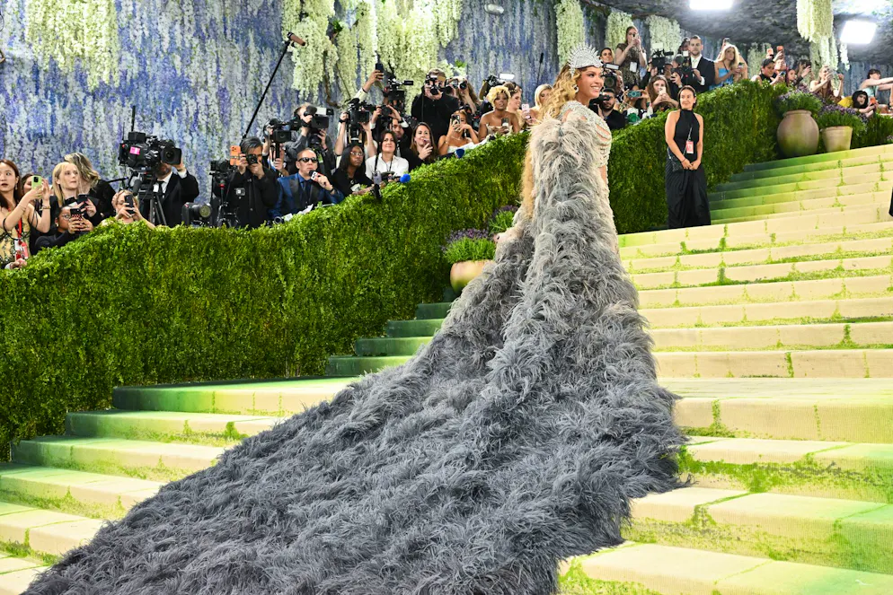 MET Gala – die Looks vom roten Teppich. Als Kontrast zum kühlen Glitzern: ein grau-beige melierter Opernmantel mit überdimensionierter Schleppe – irgendwo zwischen Gruft-Chic und königlichem Auftritt.