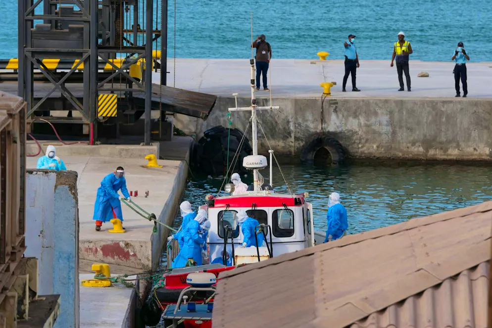 Healthcare personnel in protective clothing evacuate patients from the cruise ship "Hondius" in a port. 