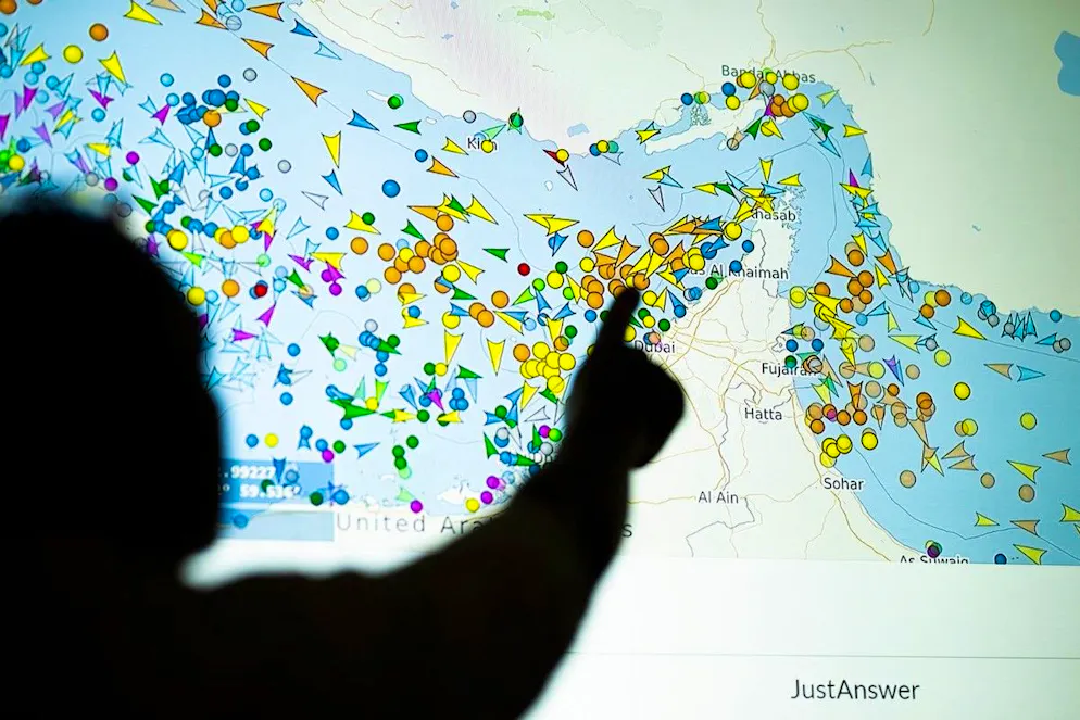 A photo illustration taken in Nicosia on May 4, 2026, shows a person in front of a large screen displaying vessel movements in the Strait of Hormuz on a ship-tracking website. Iran's navy fired 'warning shots' at US warships in the Strait of Hormuz on May 4, state media said, after the American military sent cruisers into the Gulf as part of a plan to help trapped commercial vessels leave. Earlier, US President Donald Trump had announced a plan to guide ships from neutral countries out of the Gulf, saying it was a humanitarian effort to help their stranded crews. (Photo by AFP)