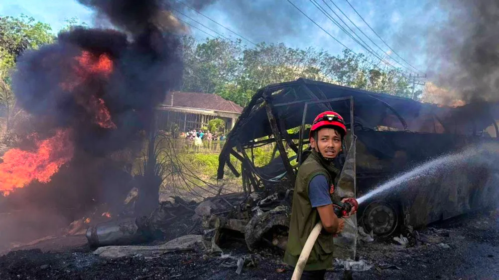 dpatopictures - HANDOUT - A rescuer tries to put out the fire after a passenger bus collided with a tanker truck in South Sumatra province. Photo: Uncredited/South Sumatra Regional Police/AP/dpa - ATTENTION: For editorial use only in connection with current reporting and only with full attribution to the above credit