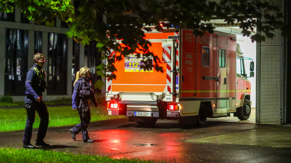 dpatopbilder – Polizisten laufen an einem ankommenden Rettungswagen vorbei, der eine deutsche Patientin in das Infektionszentrum der Uniklinik Düsseldorf bringt. Foto: Christoph Reichwein/dpa