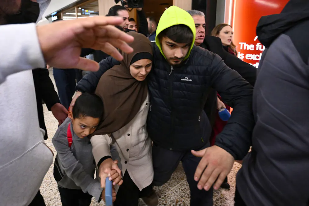 Un groupe de sympathisants entoure une femme soupçonnée d'avoir des liens avec l'État islamique alors qu'elle arrive avec un enfant à l'aéroport de Melbourne, à Melbourne, en Australie, le jeudi 7 mai 2026. (Joel Carrett/AAP Image via AP)