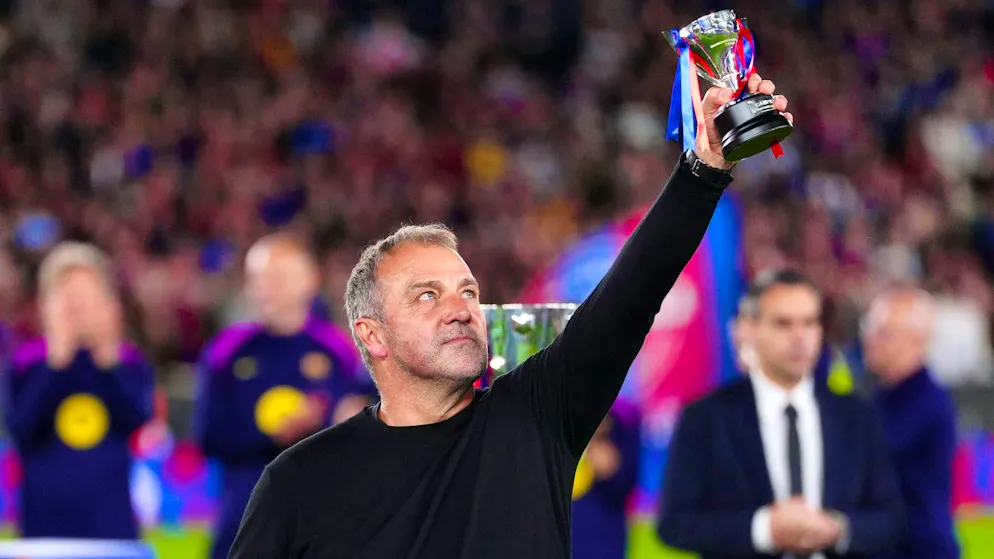 Hansi Flick raises his trophy to the sky.