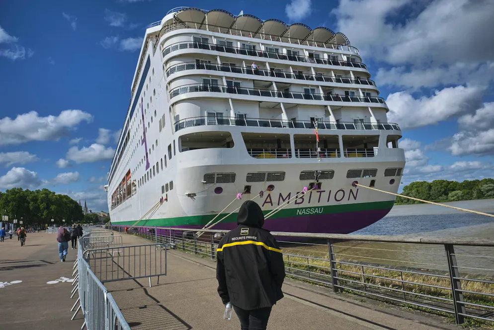 Un agent de sécurité privé se tient près du navire « Ambition » de la compagnie Ambassador Cruise Line, amarré sur les quais de la Garonne à Bordeaux, en Nouvelle-Aquitaine, dans le sud-ouest de la France, le 13 mai 2026.
