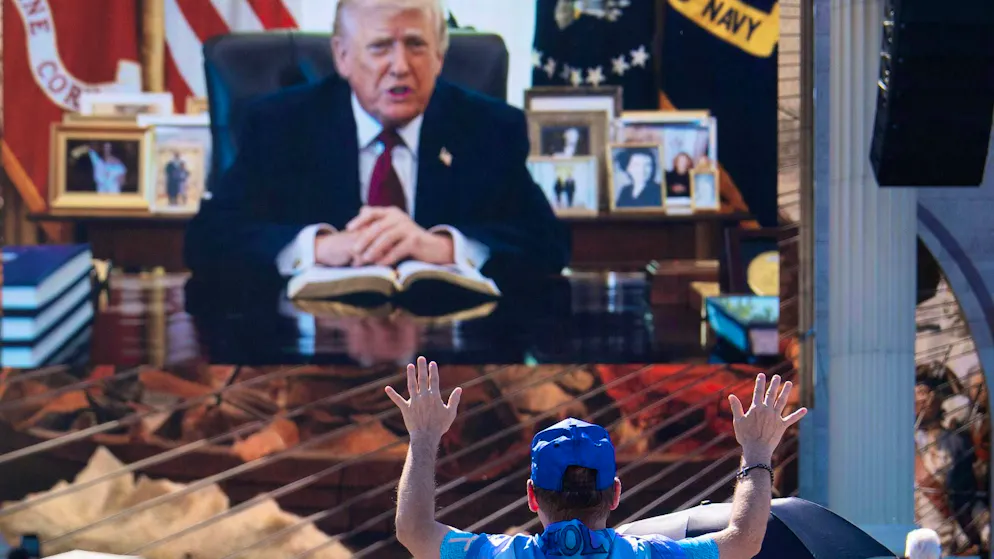 A person prays as a recorded video message from President Donald Trump is played at "Rededicate 250".