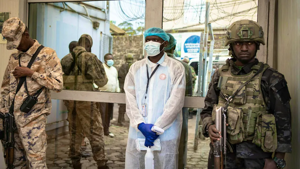 Un dipendente in abbigliamento protettivo si prepara a misurare la temperatura di un visitatore come misura preventiva contro l'ebola presso l'Istituto nazionale di ricerca biomedica di Goma, in Congo.