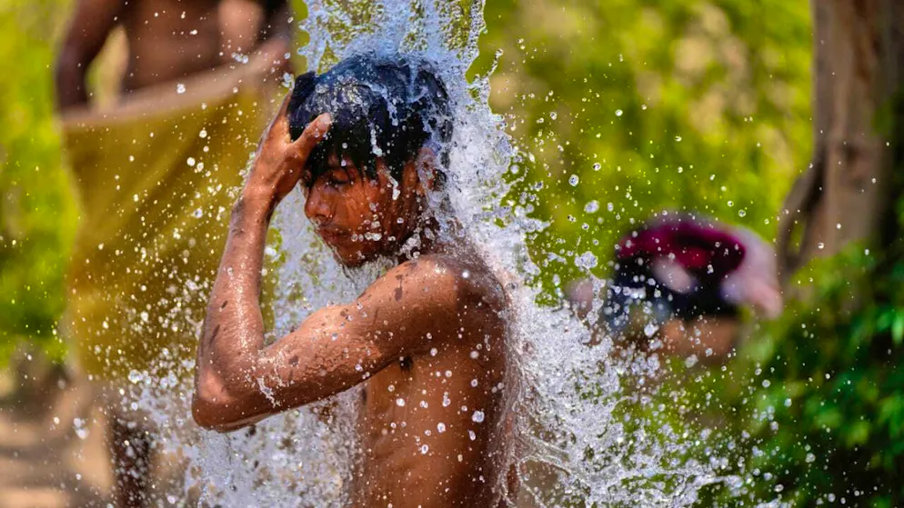 ARCHIVE - A boy cools himself at a tap on a street in India in the intense summer heat. Photo: Channi Anand/AP/dpa/Archive image