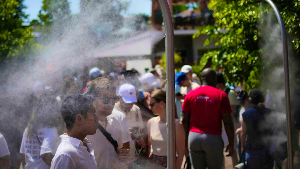 French Open visitors cool off with water from sprinklers on a hot day. Photo: Christophe Ena/AP/dpa