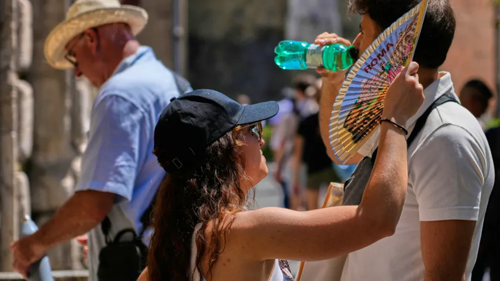 Eine Frau fächert sich Rom mit einem Fächer Luft zu, während ein Mann aus einer Wasserflasche trinkt. Foto: Gregorio Borgia/AP/dpa