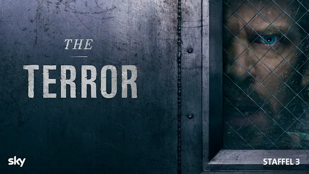 Key Art zu The Terror Staffel 3 mit einer Person hinter einem vergitterten Fenster in düsterer Horror Stimmung.