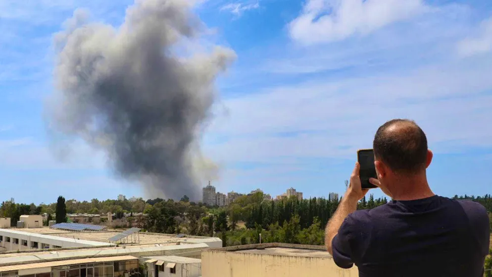 dpatopbilder - A man uses his cell phone to photograph the smoke rising after an Israeli airstrike in the southern port city of Tyre. Photo: Uncredited/AP/dpa