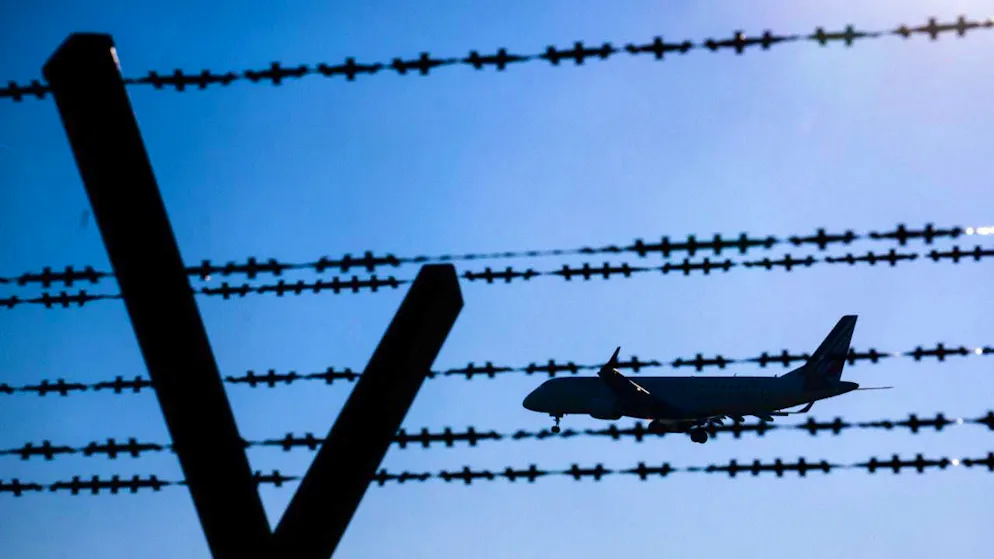 ARCHIVE - An airplane with deported migrants flies behind barbed wire at Hanover Airport. Photo: Julian Stratenschulte/dpa/Symbolic image