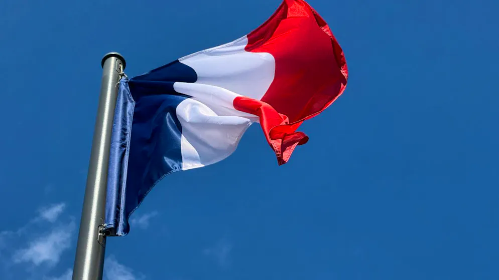 ARCHIV – Die Frankreich-Flagge, auch Trikolore genannt, weht in der Pariser Innenstadt vor blauem Himmel. Foto: Rachel Sommer/dpa