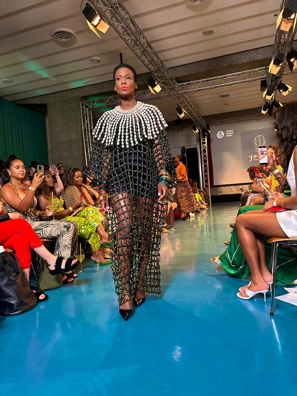 African Fashion Night 2026. At the center of every creation is the kauri - a small, oval shell. "It stands for wealth, our former currency. It recharges our energies," explains designer Roukiètou Kafando Savadogo.