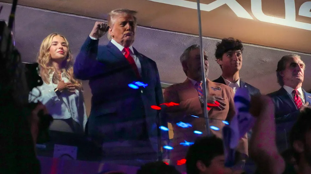 U.S. President Donald Trump raises his fist as he is booed at Madison Square Garden in his hometown of New York. On the left is his granddaughter Kai Trump, on the right are Knicks owner James Dolan and Interior Secretary Doug Burgum.
