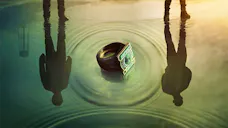 Ein grüner Ring liegt im Wasser, während sich zwei Personen an der Oberflächenspiegelung abzeichnen.